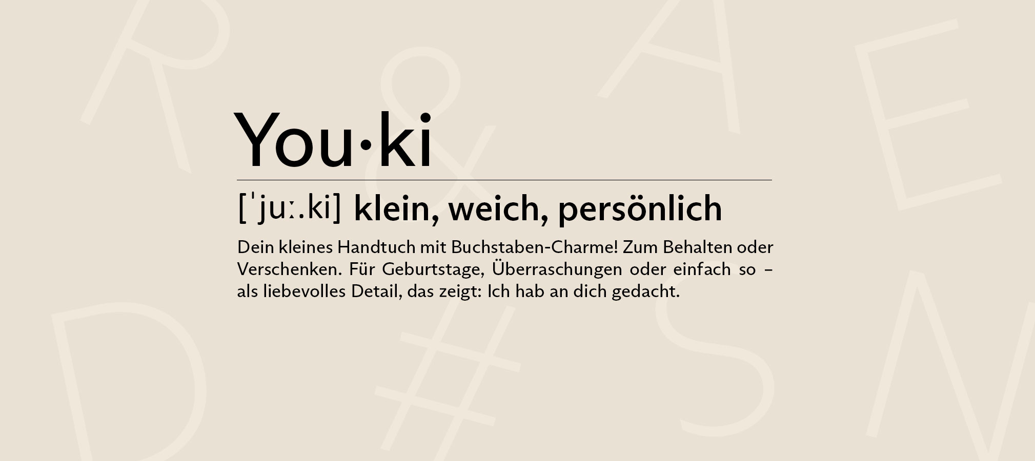 Startseiten-Banner mit beigem Hintergrund und dezent sichtbaren Buchstaben in Hellbeige, die auf das Produktthema des Shops – personalisierte Handtücher mit Buchstaben – hinweisen. In der Mitte steht eine Beschreibung des Wortes ‚Youki‘
